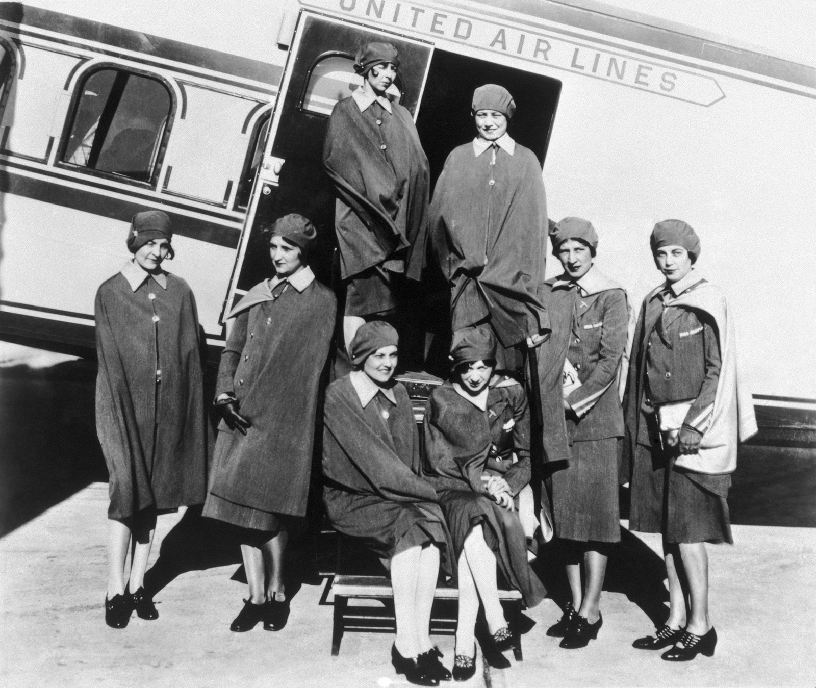 black and white photo of female flight attendants standing in doorway of Model 80 aircraft