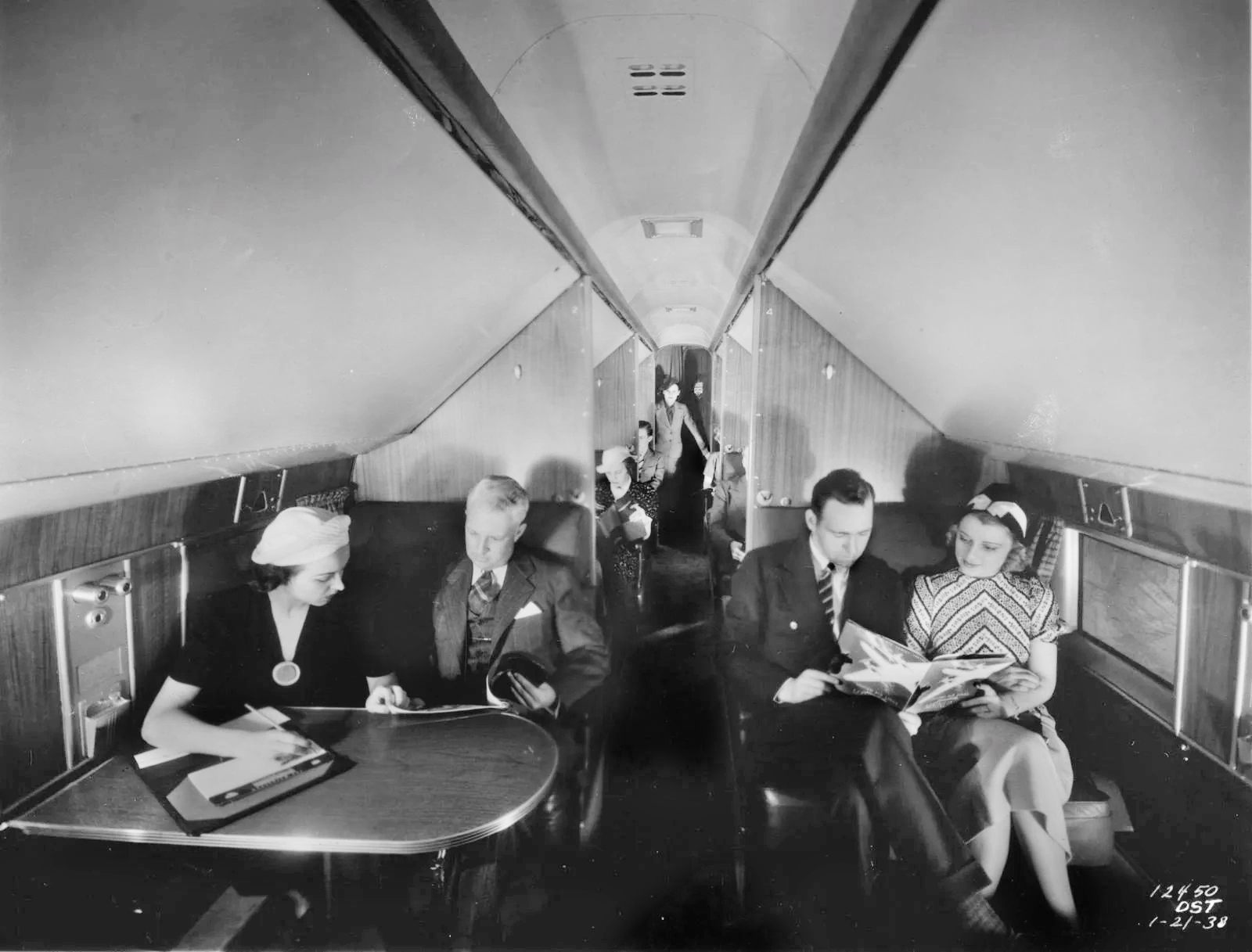 black and white photo of men and women sitting inside old aircraft