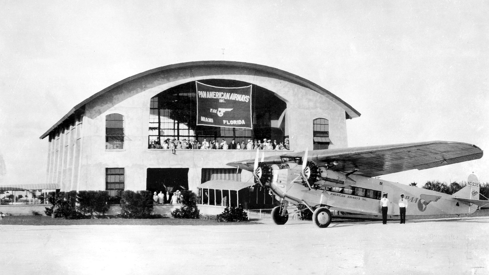 Black and white image of old Fokker aircraft on air field in front of  building