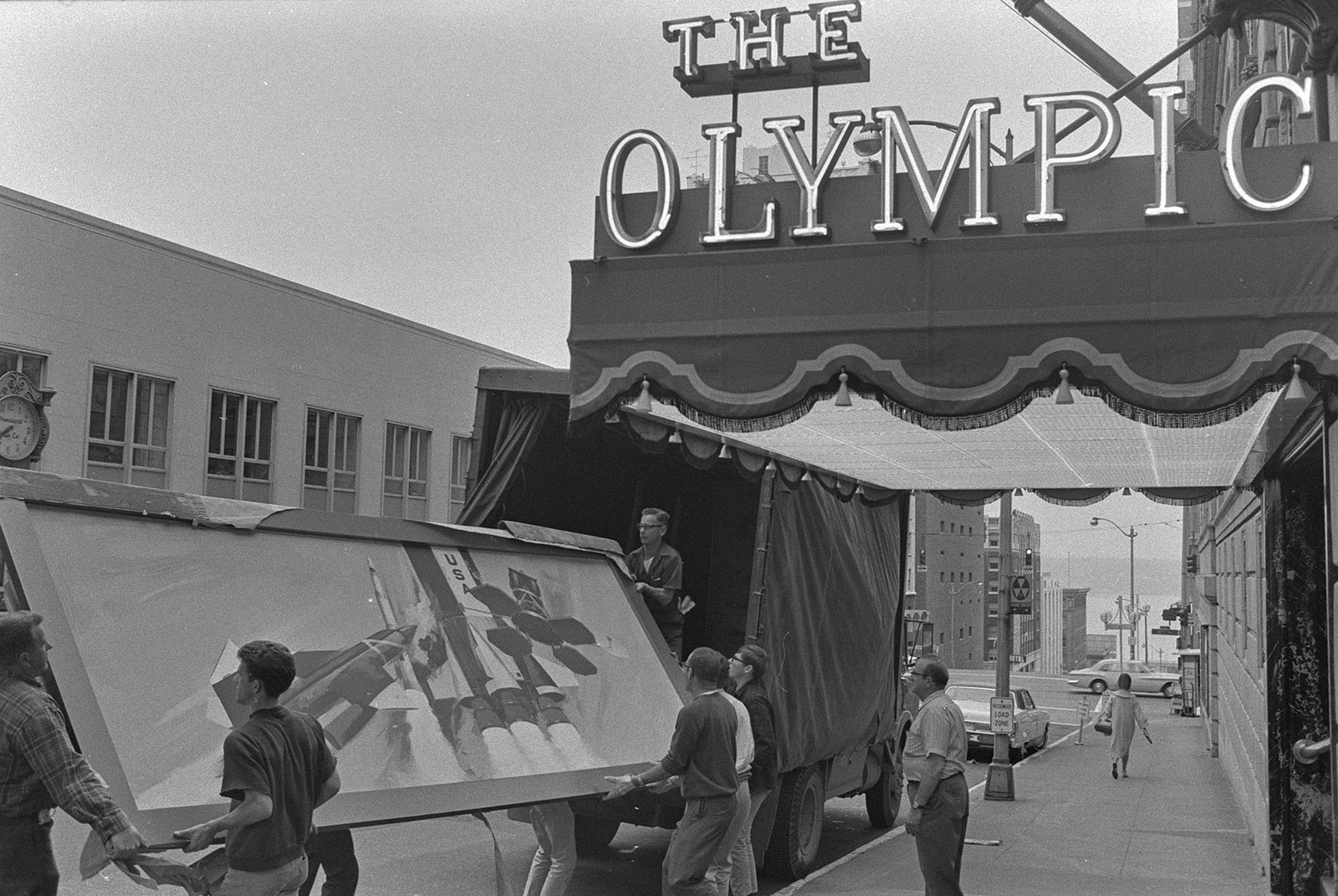 Black and white photo of employees unloading in front of hotel