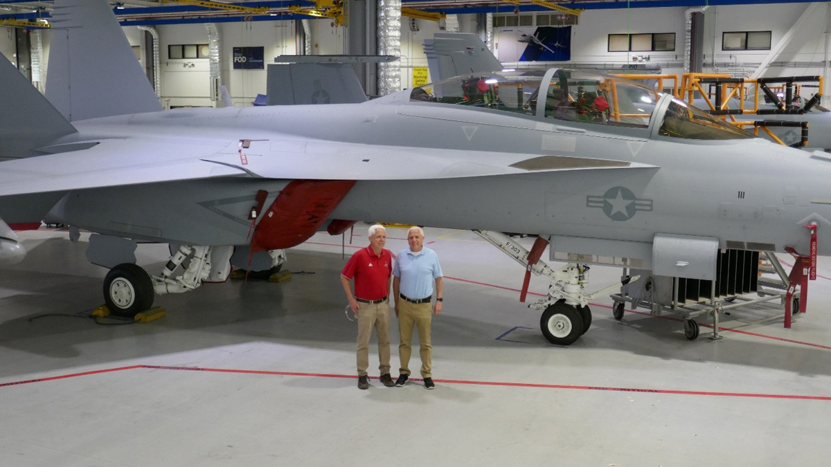 Twin engineers stand in front of a Boeing aircraft.  