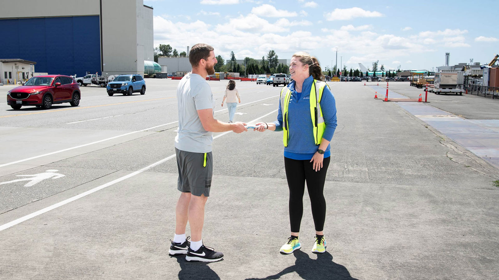 Tooling Engineering leader Logan Fouts takes hold of the baton from Everett Delivery Center Engineering senior manager Jessica Parsons for the last stretch of the relay.