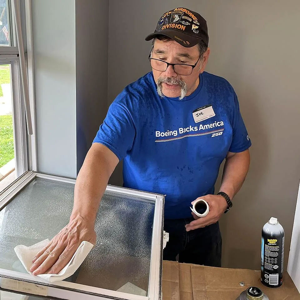 Joe Navarro, part of the Systems Engineering Integration Team, cleaning windows at Veterans Community Project of Saint Louis.