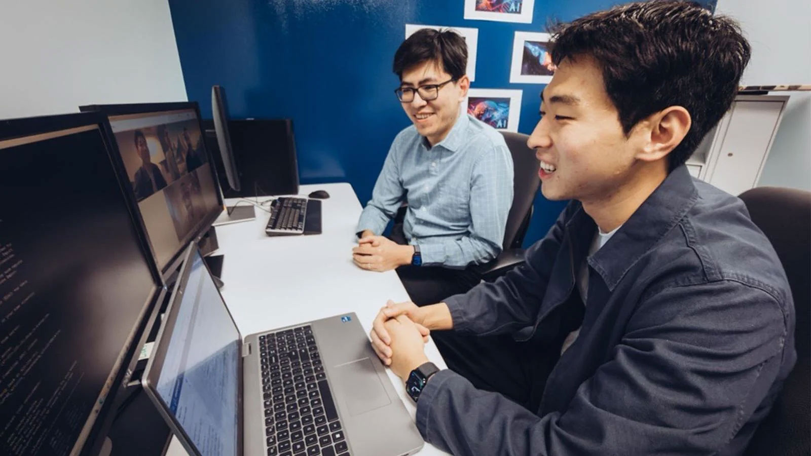 Boeing engineers Kevin Kwak (foreground) and Klaus Okkelberg confer with fellow team members Arvel Chappell and Andrew Riha (both of whom are on-screen), who worked together to prototype a large language model on space-grade hardware.