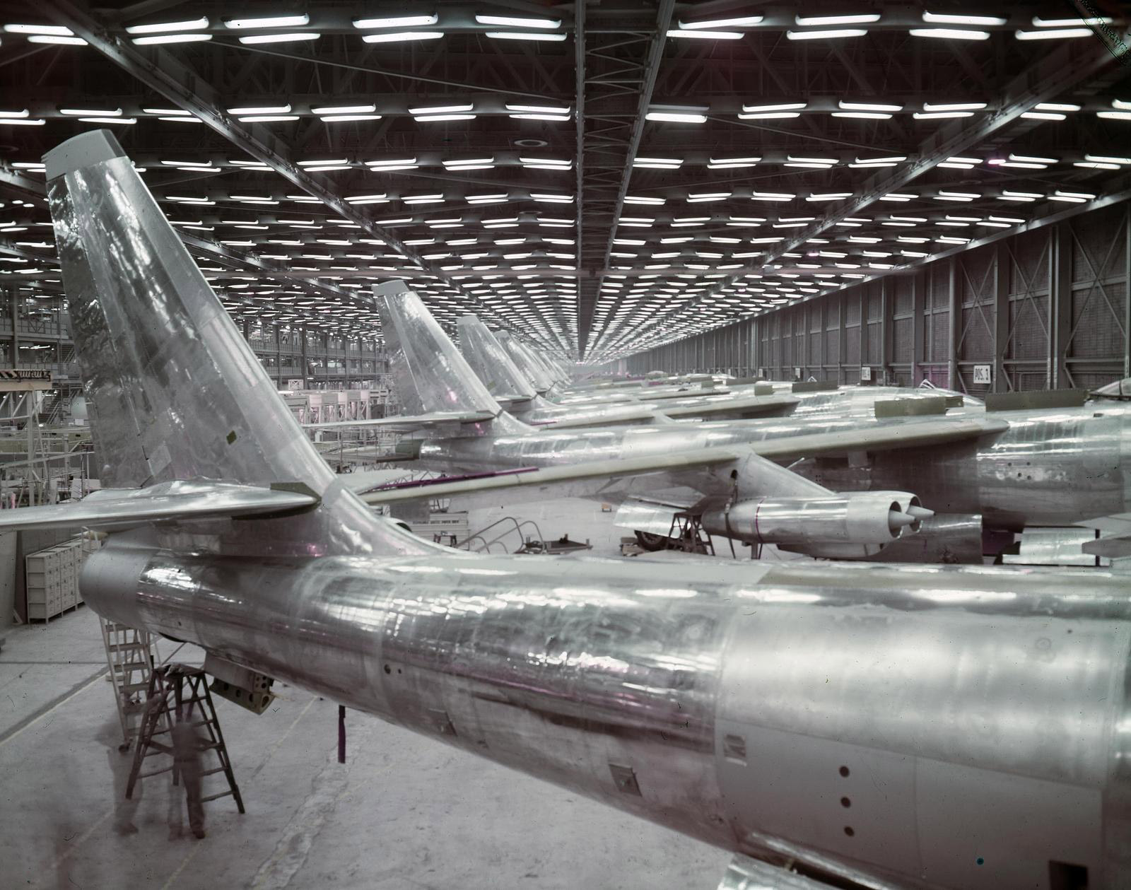 Black and white image of several planes in production.