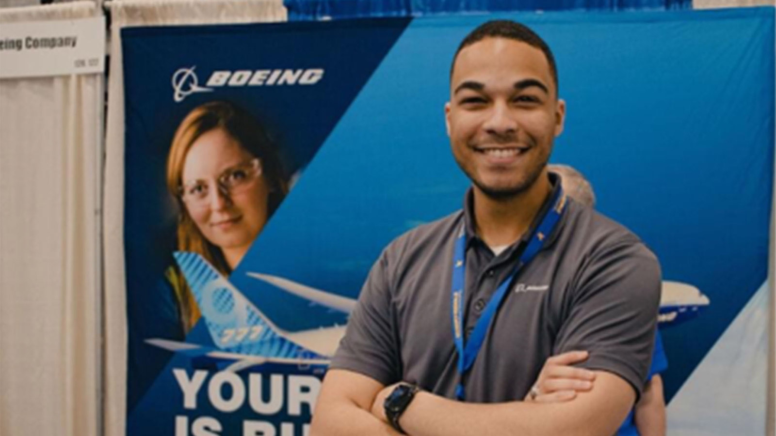 Employee stands at a Boeing booth at a recruiting event