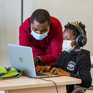 Man and child work at a laptop computer.