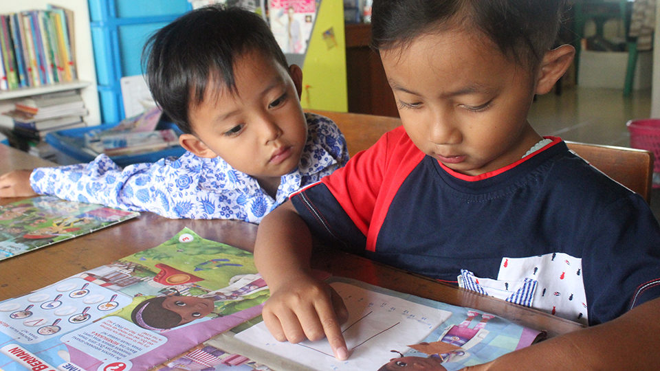 Two small childern studying a cartoon book