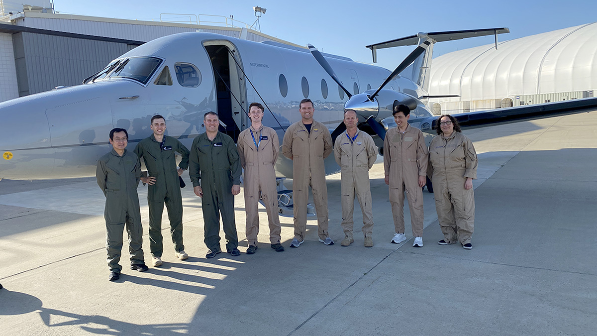 seven people stand outside flight test airplane