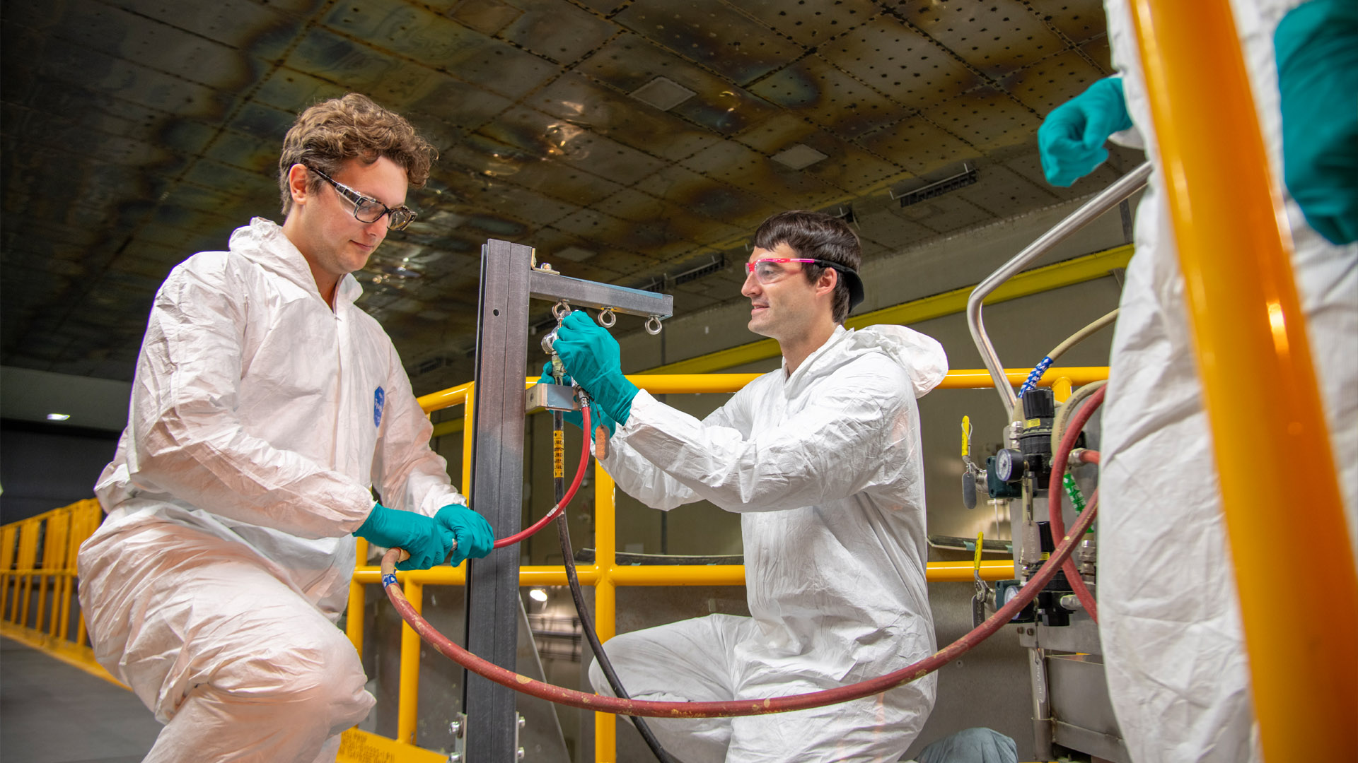 two people kneel to inspect spraying device