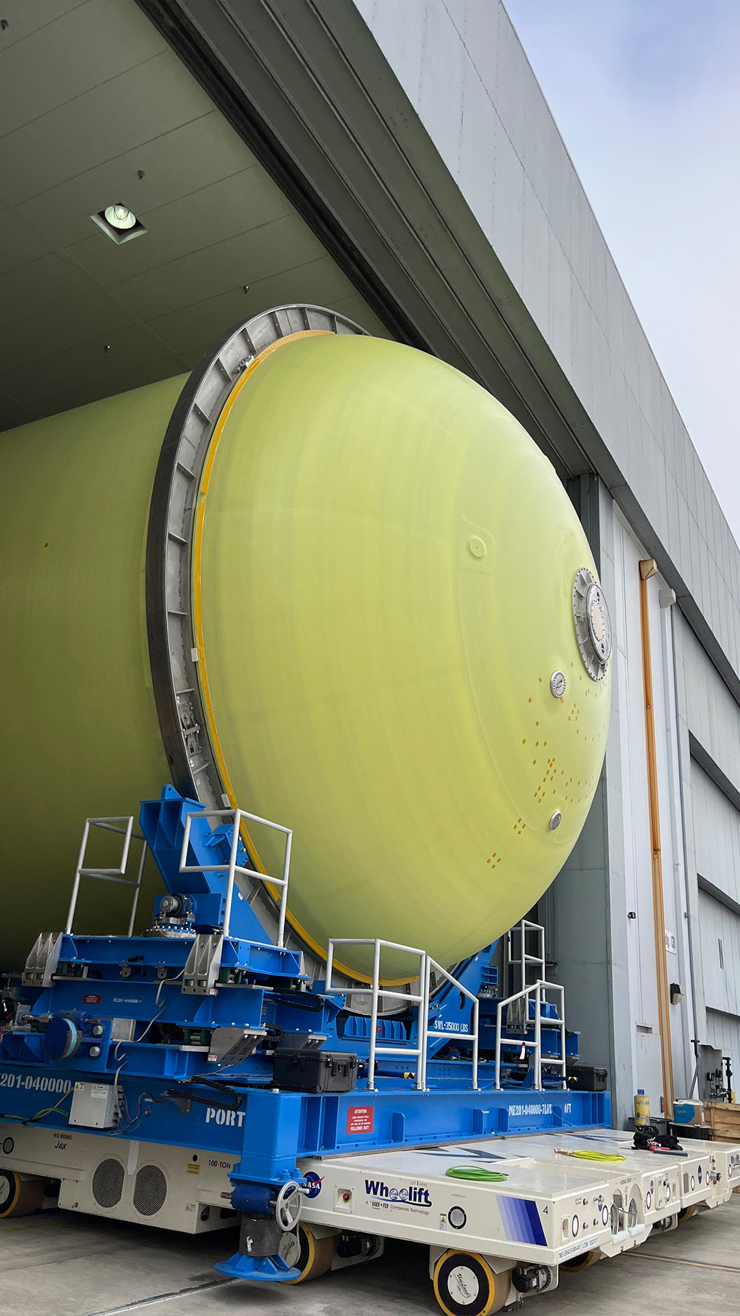 yellow SLS fuel tank dome moves out of facility