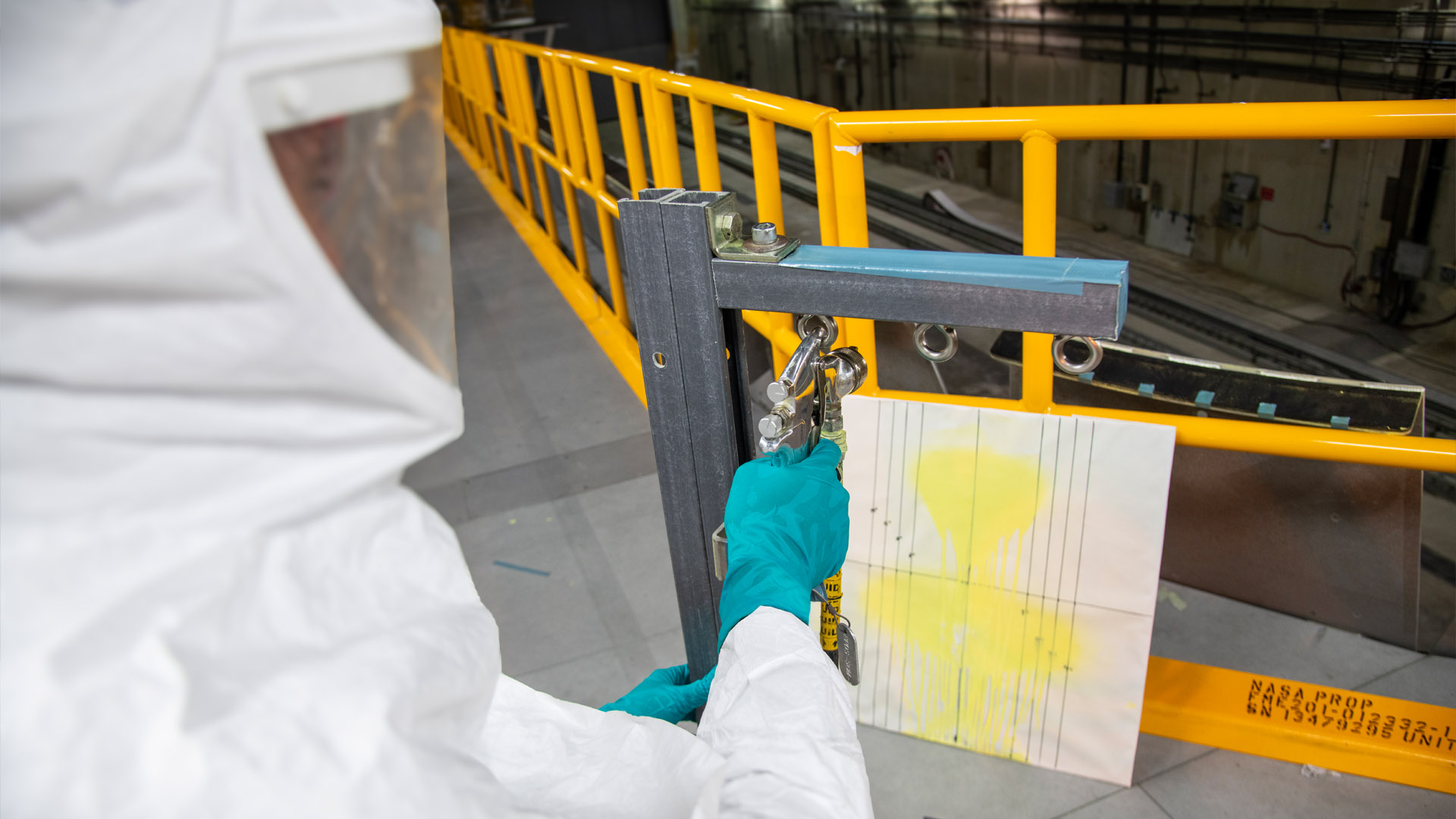 Person uses spraying device to apply primer  to test board