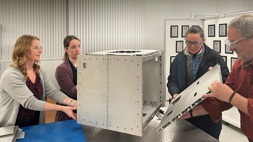Four Boeing engineers assemble small satellite structure