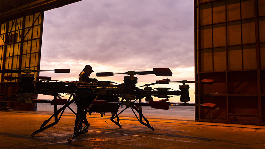 Silhouetted individual works on cargo air vehicle inside hangar