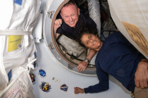 June 13, 2024) — NASA’s Boeing Crew Flight Test astronauts (from top) Butch Wilmore and Suni Williams pose for a portrait inside the vestibule between the forward port on the International Space Station’s Harmony module and Boeing’s Starliner spacecraft.