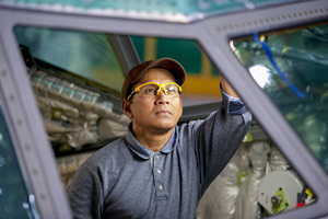 Man wearing safety glasses inside of unfinished commercial cockpit installing windows