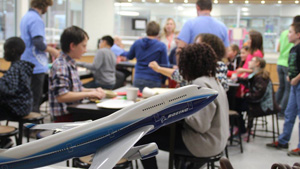 Model of 747 in Boeing livery with classroom and kids in background.