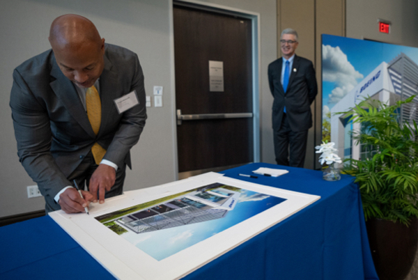 Howard McKenzie signs an artist's rendering of the Boeing Center for Aviation and Aerospace Safety at Embry-Riddle Aeronautical University.