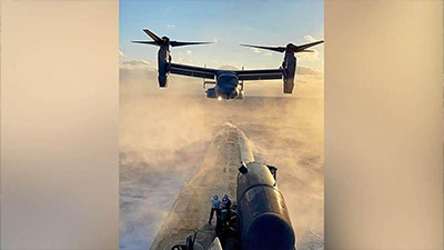 Sky meets sea as a CV-22 Osprey hovers over a submarine