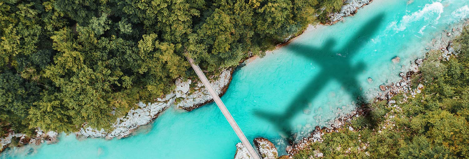 Aerial picture of forest river and the shadow of a Boeing airplane.