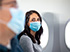 A woman with a safety mask sitting on a plane.