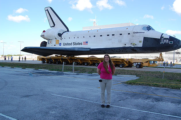 Nalena Kennett standing in front of the space shuttle Endeavor