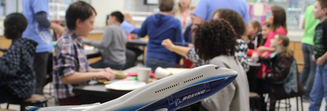 Picture of Students in a learning environment with Boeing airplane in foreground.
