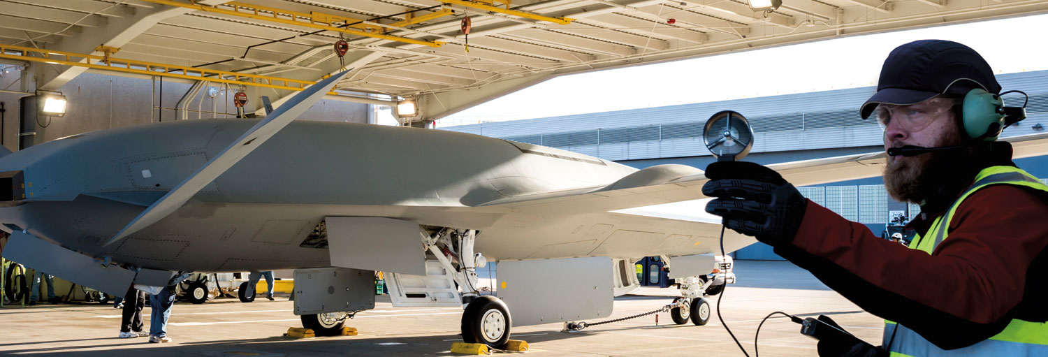 Employee measuring environment with MQ-25 in the background