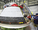Picture of Boeing technicians installing the backshells on the Orbital Flight Test 2 Crew Module.
