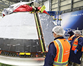 Picture of Boeing technicians installing the backshells on the Orbital Flight Test 2 Crew Module.