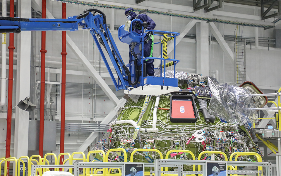 Picture of technician maneuvering lift to access work area on Spacecraft 3 upper dome.