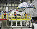 Picture of Boeing technicians installing the backshells on the Orbital Flight Test 2 Crew Module.